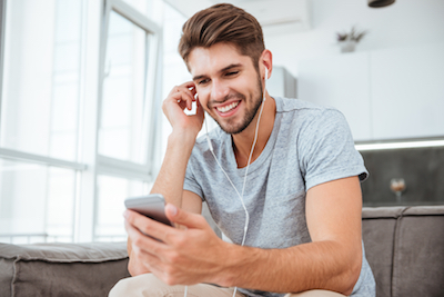 Happy Man Listening To Music While Sitting On Sofa